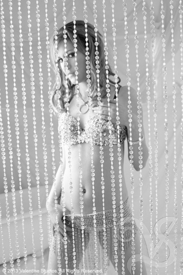 beautiful woman peering through the beads during her boudoir photo shoot at Valentine Studios in San Diego, CA.